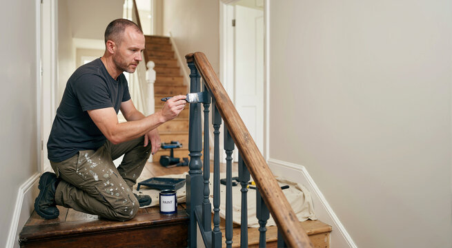 Man painting stair railing. Home renovation project. DIY repair concept
