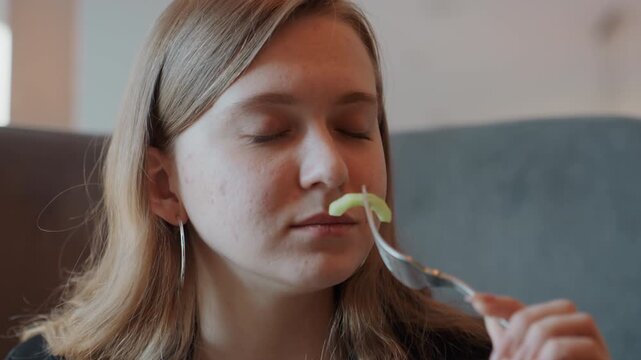 Quiet woman observes lettuce carefully. Serene lady closely reviews her fresh greens. Calm female diner thoughtfully inspects forkful of fresh lettuce in intimate restaurant setting