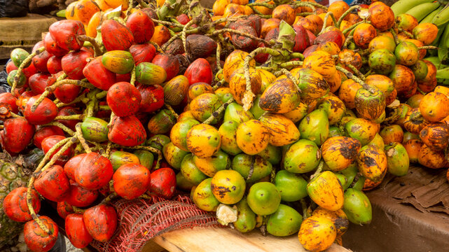 Clusters of fresh red and yellow chontaduro fruits displayed at a traditional market, showcasing vibrant tropical colors and organic textures.