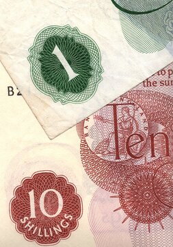 A close up detail of ten shillings and one pound banknotes from the United Kingdom.