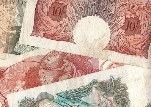 A close up detail of ten shillings and one pound banknotes from the United Kingdom.