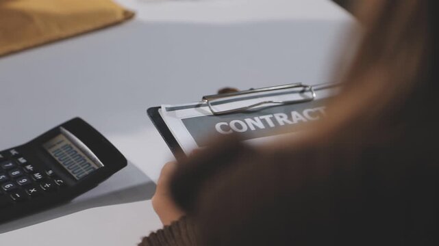 Female attendant handed over the rental car key to the customer who signed the contract and the terms of the agreement on the document, Car rental service concept.