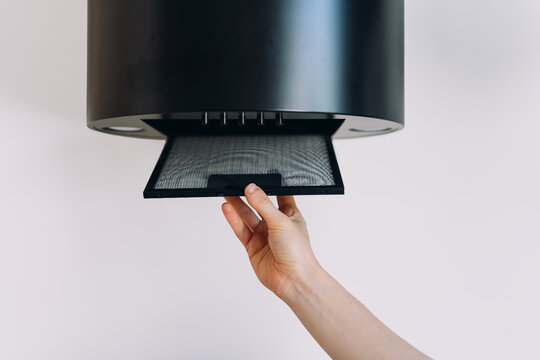 Woman remove kitchen hood filter for cleaning from dust