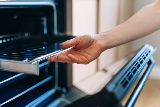 Woman remove metal grill from oven in kitchen