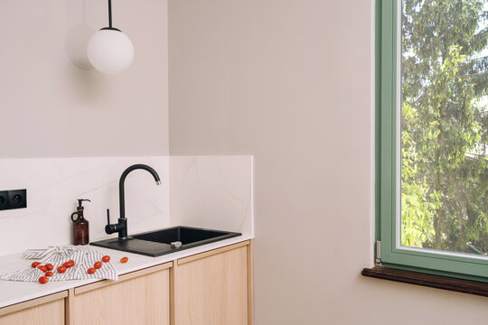 Modern kitchen corner with black sink, faucet, and wooden cabinets