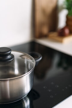 Close up shot of induction hob with stainless steel pot and glass lid