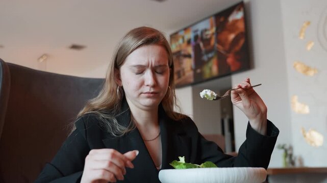 Caucasian woman rejecting salad with displeasure, professional diner examining forkful and grimacing, modern interior with ambient lighting, candid reaction during lunch, menu evaluation and taste