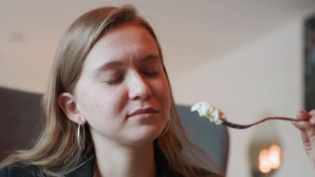Caucasian woman tasting salad with fork, closeup portrait in cozy bistro, food blogger savoring fresh greens and creamy dressing, gentle smile and thoughtful expression, soft ambient lighting