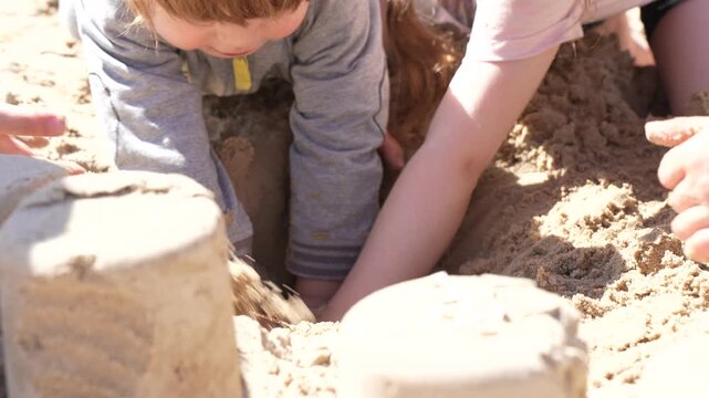 Group of young children digging deep holes in a sandbox together showcasing teamwork friendship and early childhood development during outdoor summer activity