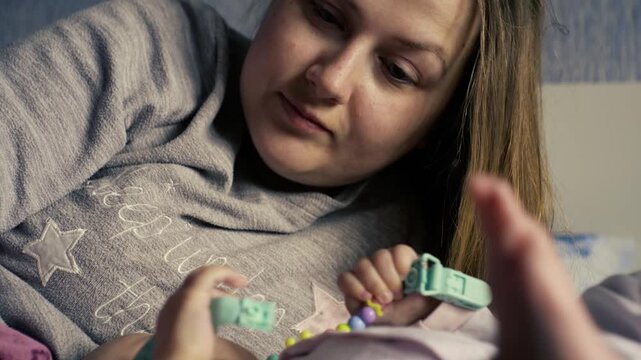 Authentic close up shot of young neo mother is playing with her newborn baby in a nursery in a morning. Concept of children,baby, parenthood, childhood, life, maternity, motherhood