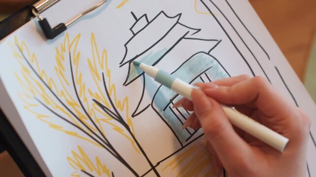 Closeup white artist coloring pagoda roof with blue marker on clipboard sketch, warm studio light, delicate ink lines, wheat branches drawing, steady hand strokes, cozy creative mood, tutorial pace