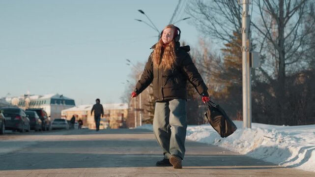 Woman on snowbound roadside seeks transport. Female traveler pauses by icy street hoping for lift home. Woman waiting by snowcovered path in hopes of catching passing vehicle to continue journey