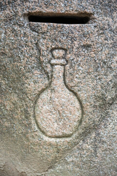 Macro shot of traditional stone donation box with bottle carving at buddhist temple.