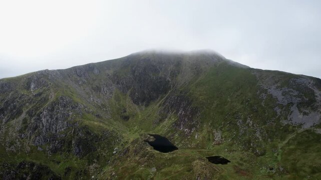 Aerial Drone View of Hidden Mountain Tarn Beneath Misty Summit in Snowdonia