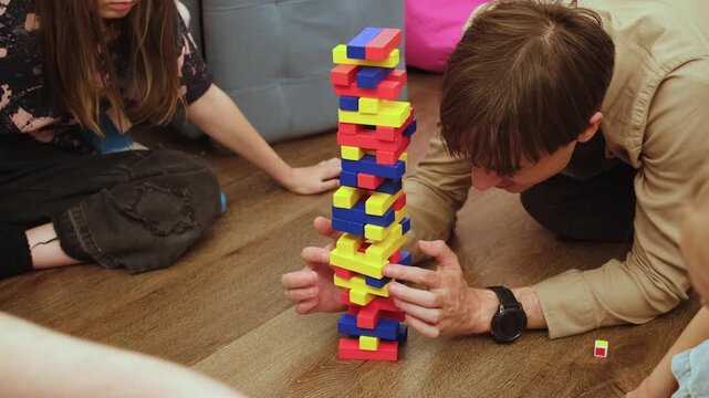 Playing Jenga with kids, family playing board games, home entertainment