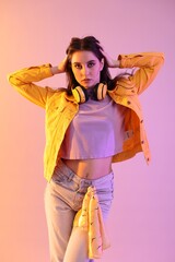 Young hip-hop dancer in stylish clothes posing on color background