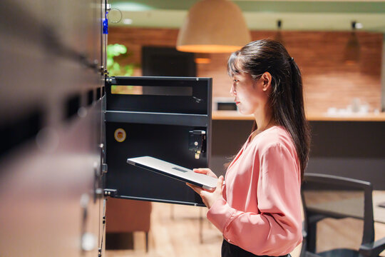 会社のロッカーでPCを保管する女性社員
