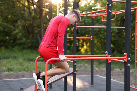 Athletic young man exercising on parallel bars at outdoor gym