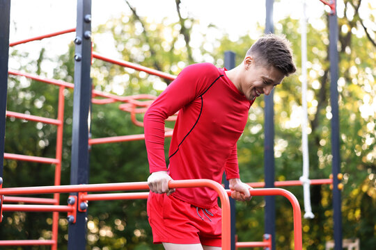 Athletic young man exercising on parallel bars at outdoor gym