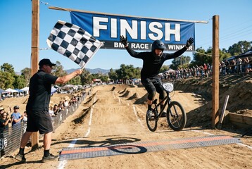 Fototapeta premium Exciting BMX Race Finish: A Cyclist Celebrates Victory Crossing the Finish Line with Enthusiasm