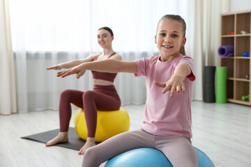 Obraz premium Little girl and trainer exercising with fitness balls indoors, selective focus