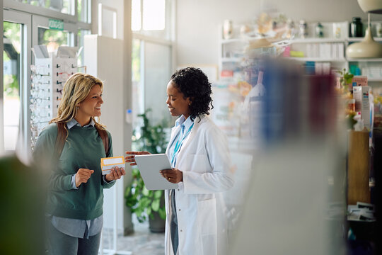 Happy woman consulting with her pharmacist while buying vitamins in pharmacy.