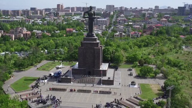 Aerial view of the Mother Armenia monument in Yerevan, featuring a military ceremony at the base of this giant statue on a bright sunny day in late spring.

