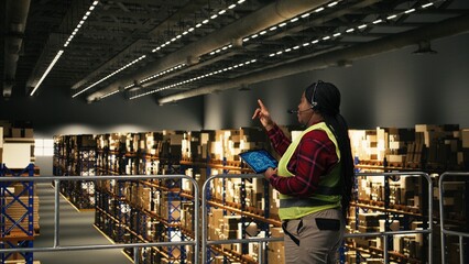 African American female staff using headset to handle package tracking, cargo status and customer...