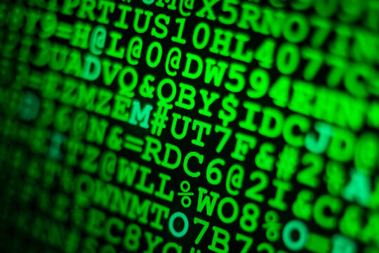 Glowing green computer code and hexadecimal numbers displayed on a dark screen with shallow depth of field