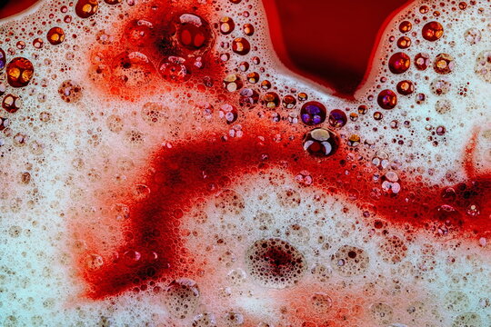 Schiuma da detergente con bolle e bollicine colorate in liquido rosso