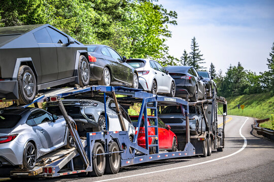Car hauler transporting cars and crossovers on the two level semi trailer running on the winding mountain narrow road