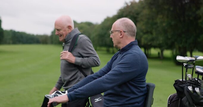Friends, senior men or pointing at golf course with conversation, equipment and bag outdoor on grass field. Golfers, elderly people or talking in nature for sport, golfing or recreation for fitness