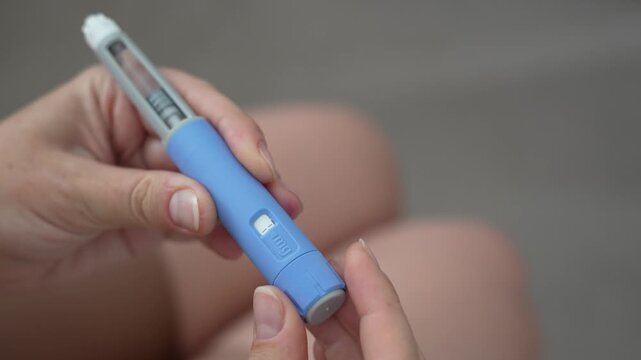 Woman setting dosage clicks on GLP-1 injection pen close-up