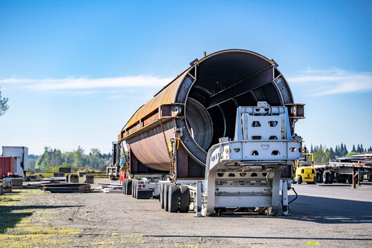 Heavy duty semi trailer loaded with oversize cargo waiting for the big rig semi truck standing on the industrial parking lot