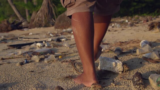 Bare Feet on a Polluted Beach Shoreline with Plastic Waste and Debris, Highlighting Coastal Pollution and Environmental Awarenes
