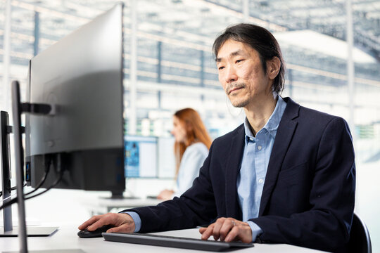 Senior engineer in microchip factory RD office conducting feasibility study on SoC architecture design, Asian man developing roadmaps for innovative semiconductors technology.