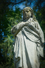 Obraz premium Stone angel statue standing peacefully in cemetery garden.