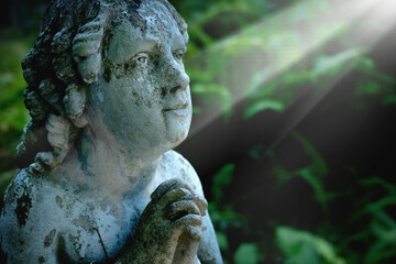 Obraz premium Beautiful cherub angel statue illuminated by heavenly rays of light.