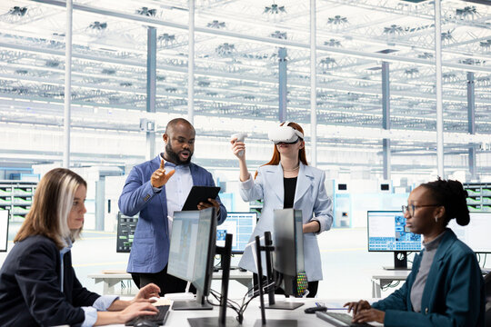 Multiracial team testing microchip electronics prototypes using VR, brainstorming, Teamworking colleagues using virtual reality goggles to upgrade industrial hardware in semiconductors RD laboratory.