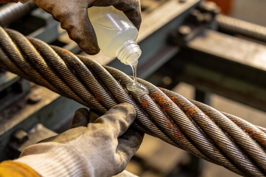 Person applying lubricant to metal cable
