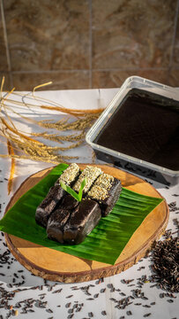 Traditional Indonesian Black Glutinous Rice Dodol Cake on Banana Leaf with Sesame Topping (Jenang Ketan Hitam)