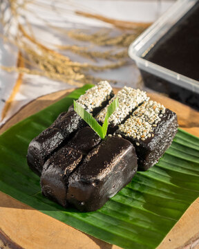 Traditional Indonesian Black Glutinous Rice Dodol Cake on Banana Leaf with Sesame Topping (Jenang Ketan Hitam)