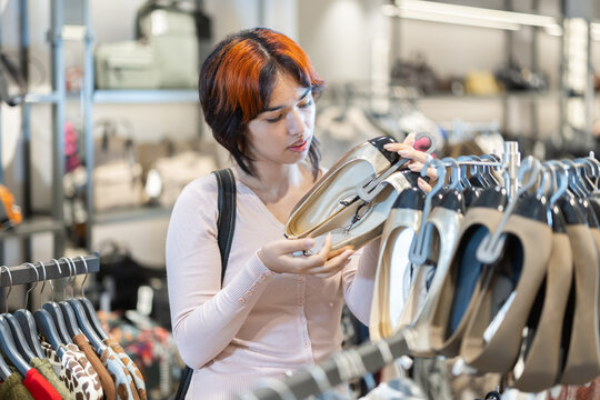 Attentive young girl choosing footwear in clothing shop with large collection