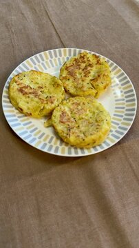 Three potato pancakes on plate, crispy golden draniki seasoned with pepper and herb flakes, served on patterned ceramic plate