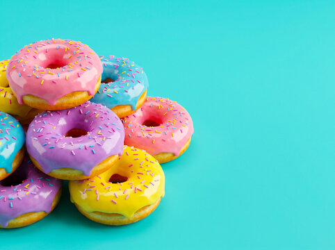 Stack of colorful glazed donuts with sprinkles on a blue background