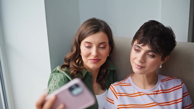 Smiling women making selfie cellphone posting content to social media closeup. 