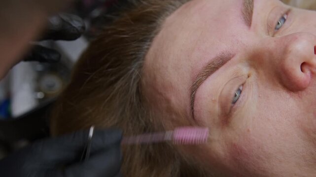 Watch as a skilled beautician expertly tattoos eyebrows using a needle machine, creating a flawless look. The process involves precise techniques and vibrant pigments for perfect brows