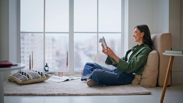Woman waving hand tablet web camera sitting by home window. Lady video calling
