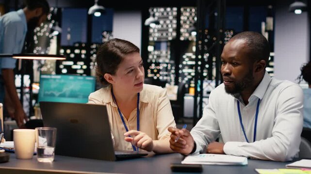 Diverse coworkers on laptop managing tasks and documenting project progress. Team engaging in brainstorming, research and data analysis while aligning objectives to meet business goals.