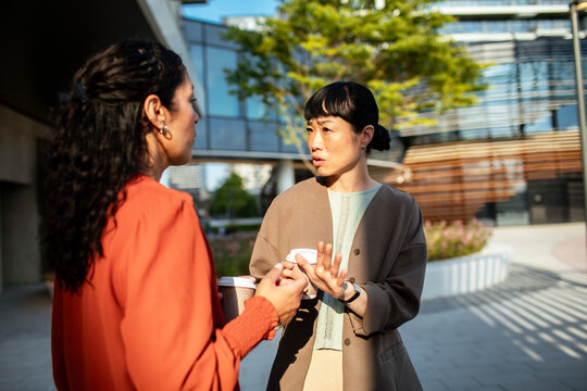 Two colleagues discussing work outside modern office